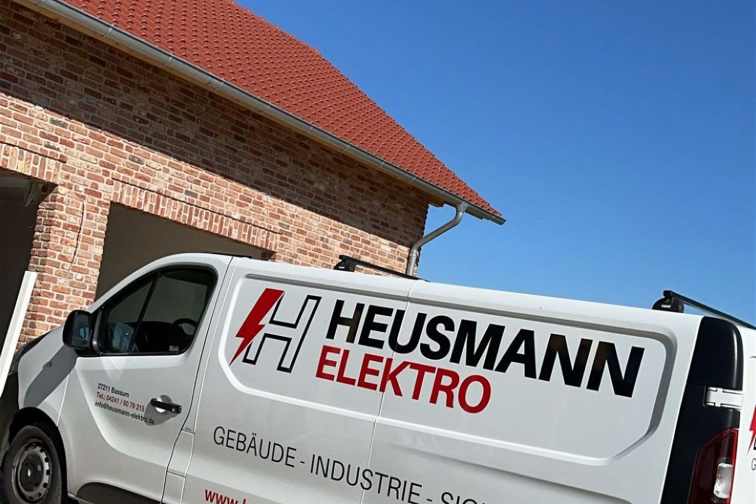 Servicefahrzeug von Heusmann Elektro vor einem Neubau